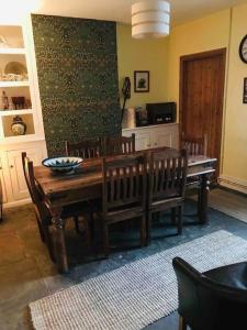 a dining room with a wooden table and benches at Harvel Cottage in Paulton