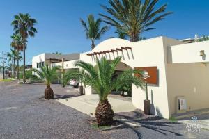 a white building with palm trees in front of it at Oceanview Stay, Satellite Internet, Steps to Beach in El Sargento