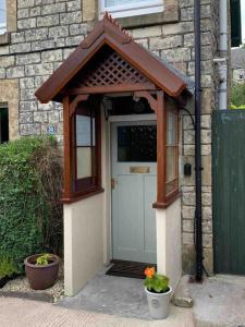 ein kleines Haus mit einer Tür mit einem Dach in der Unterkunft Harvel Cottage in Paulton