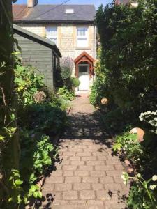 a brick walkway leading to a house with a door at Harvel Cottage in Paulton