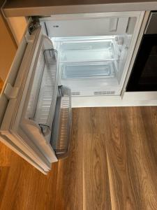 an empty refrigerator with its door open on a wooden floor at Luxury Studio Apartment by Central Stay in Liverpool