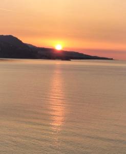 una puesta de sol sobre un cuerpo de agua con la puesta de sol en Appartamento un mare di fiori, en Ventimiglia