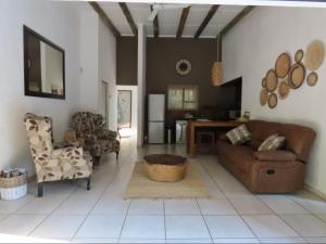 een woonkamer met een bank, stoelen en een tafel bij Marloth Cottage in Marloth Park