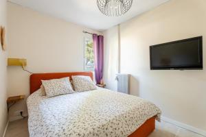 1 dormitorio con 1 cama y TV de pantalla plana en La Saltarelle par Dodo à Cassis, en Cassis