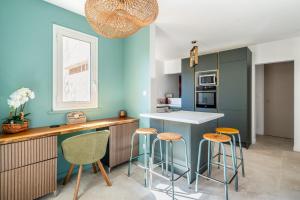 una cocina con paredes azules y taburetes de bar en La Saltarelle par Dodo à Cassis, en Cassis