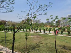 a park with trees and a person standing on a swing at homeystay urbandream service apartment in Faridabad