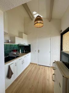 duża kuchnia z białymi szafkami i dużymi drzwiami w obiekcie Appartement 2 chambres vue sur lac marin à Barcarès w mieście Le Barcarès