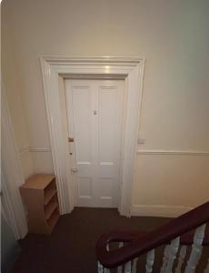 um corredor com uma porta branca e um estojo de escadas em A sunny flat near town centre em Brighton & Hove