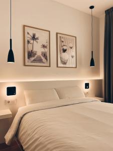 1 dormitorio con 1 cama blanca y 3 cuadros en la pared en Hotel Bonaire, en L'Escala