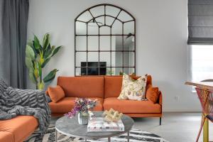 an orange couch in a living room with a glass table at Gdańsk Old Town Scala Premium Apartments D with Parking by Lion Apartments in Gdańsk