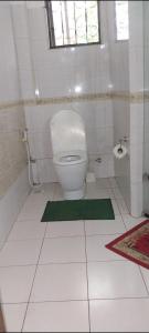 PALM SEAVIEW LUXURY HOMESTAY - SEBULENI APARTMENTS - Nyali Mombasa في مومباسا: حمام مع مرحاض وسجادة خضراء