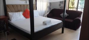 Schlafzimmer mit Himmelbett und Sofa in der Unterkunft PALMS SEAVIEW LUXURY HOMESTAY - SEBULENI APARTMENTS - Nyali Mombasa in Mombasa