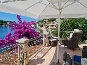 a patio with a white umbrella and purple flowers at Villa Agata in Lastovo