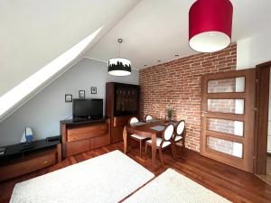 a living room with a table and a brick wall at Agapella Apartamenty - Apartament Sopot Attic in Sopot