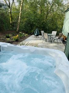 a hot tub in a backyard with chairs and a table at Southfield Shepards Huts in Durham