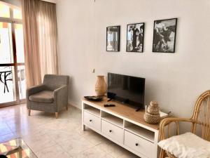 a living room with a flat screen tv and a chair at Beautiful bungalow on the Torrox-Costa boulevard! in Málaga