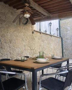 un tavolo in legno con sedie e un ventilatore a soffitto di A casiña de Estela a Caldas de Reis