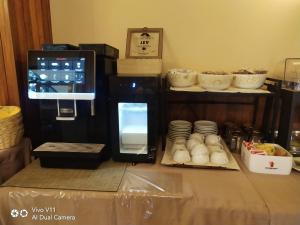a counter with a coffee maker and a table with cups at Hotel Garden in Torri del Benaco