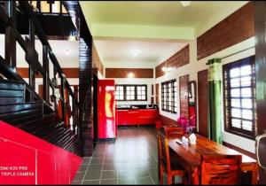 a dining room with a table and a red kitchen at V stays in Kushālnagar