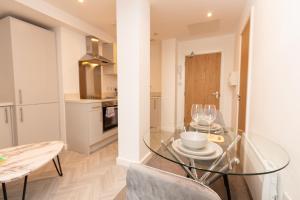 a dining room with a glass table and a kitchen at Cosy Retreat in the heart of Preston in Preston
