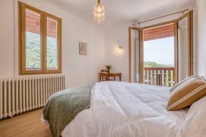 a bedroom with a white bed and a balcony at Auberge du pont de l'Abîme in Gruffy