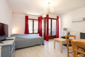 a bedroom with red curtains and a bed and a desk at Studio meublé in Aix-les-Bains