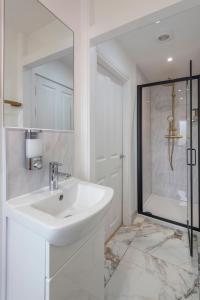 uma casa de banho branca com um lavatório e um chuveiro em BRAND NEW The Palms: Luxury Family Residence em Londres