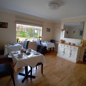 una sala da pranzo con tavoli, sedie e specchio di Edencrest B&B a Bantry