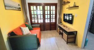 un soggiorno con divano arancione e scrivania di #residencialvillajeri - CASA térrea com VARANDA, máq de lavar, 300m da PRAIA a Jericoacoara