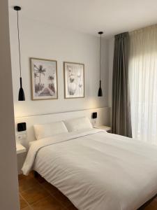 a bedroom with a white bed and two pendant lights at Hotel Bonaire in L'Escala