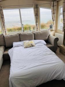 a bed in a room with a couch and windows at Stunning Caravan on Swanage Bay View Holiday Park in Swanage