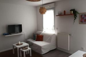 Una sala de estar con un sofá blanco y un televisor. en Charmant appartement cosy et paisible proche Paris - métro à 2min, en Romainville