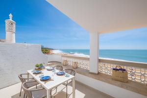 a balcony with a table and chairs and a lighthouse at Casa na Muralha - Beach front - Rooftop Jacuzzi by DreamvillasAlbufeira in Albufeira +16 photos