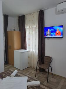 a bedroom with a tv on the wall and a chair at Casa Ancuta in Eforie Sud