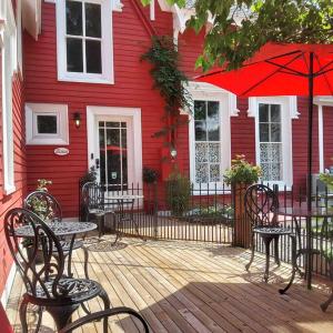 una casa roja con mesas y sillas en una terraza de madera en The Red House Fredericton en Fredericton