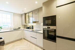 a kitchen with white cabinets and black appliances at Holland Park Residence in London