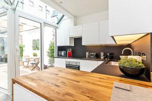 a kitchen with white cabinets and a wooden counter top at The Secret KENSINGTON Garden Mews-2 Bedroom FULL HOUSE-2 Train Lines- SPACIOUS-Kings Road- Harrods -Chelsea Stadium-PRIVATE small patio in London