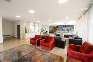 a living room with a couch and red chairs at Colonial Flat Hotel in Itapetininga