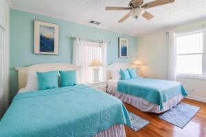 two beds in a bedroom with blue walls and wooden floors at Ocean Queen in Tybee Island