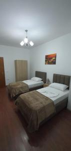 two beds in a room with a ceiling fan at City Center Apartment in Shkodër