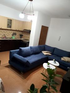 a living room with a blue couch and a kitchen at City Center Apartment in Shkodër