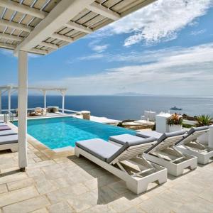 a swimming pool with lounge chairs and the ocean at Stunning 7-Bed Villa Villa Panamera in Psarou