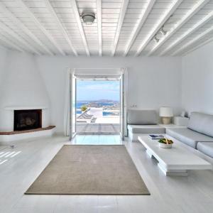 a white living room with a couch and a fireplace at Stunning 7-Bed Villa Villa Panamera in Psarou