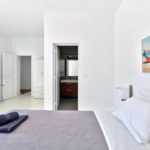 a white bedroom with a bed and a bathroom at Stunning 7-Bed Villa Villa Panamera in Psarou