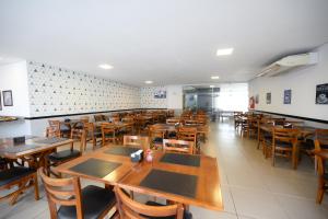 an empty restaurant with wooden tables and chairs at Colonial Flat Hotel in Itapetininga