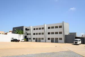 a white building with cars parked in a parking lot at Colonial Flat Hotel in Itapetininga