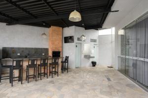 a room with a kitchen and a bar with chairs at Colonial Flat Hotel in Itapetininga