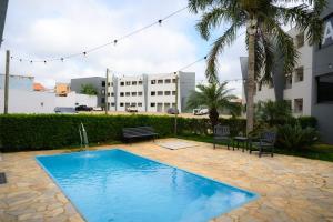a swimming pool with two chairs and a building at Colonial Flat Hotel in Itapetininga