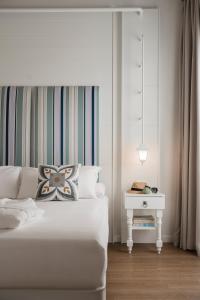 a white bedroom with a white bed and a nightstand at Luxor Cattolica Beach Hotel in Cattolica