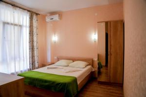 Un dormitorio con una cama con sábanas verdes y una ventana en Bukhta №5 Guest House, en Adler